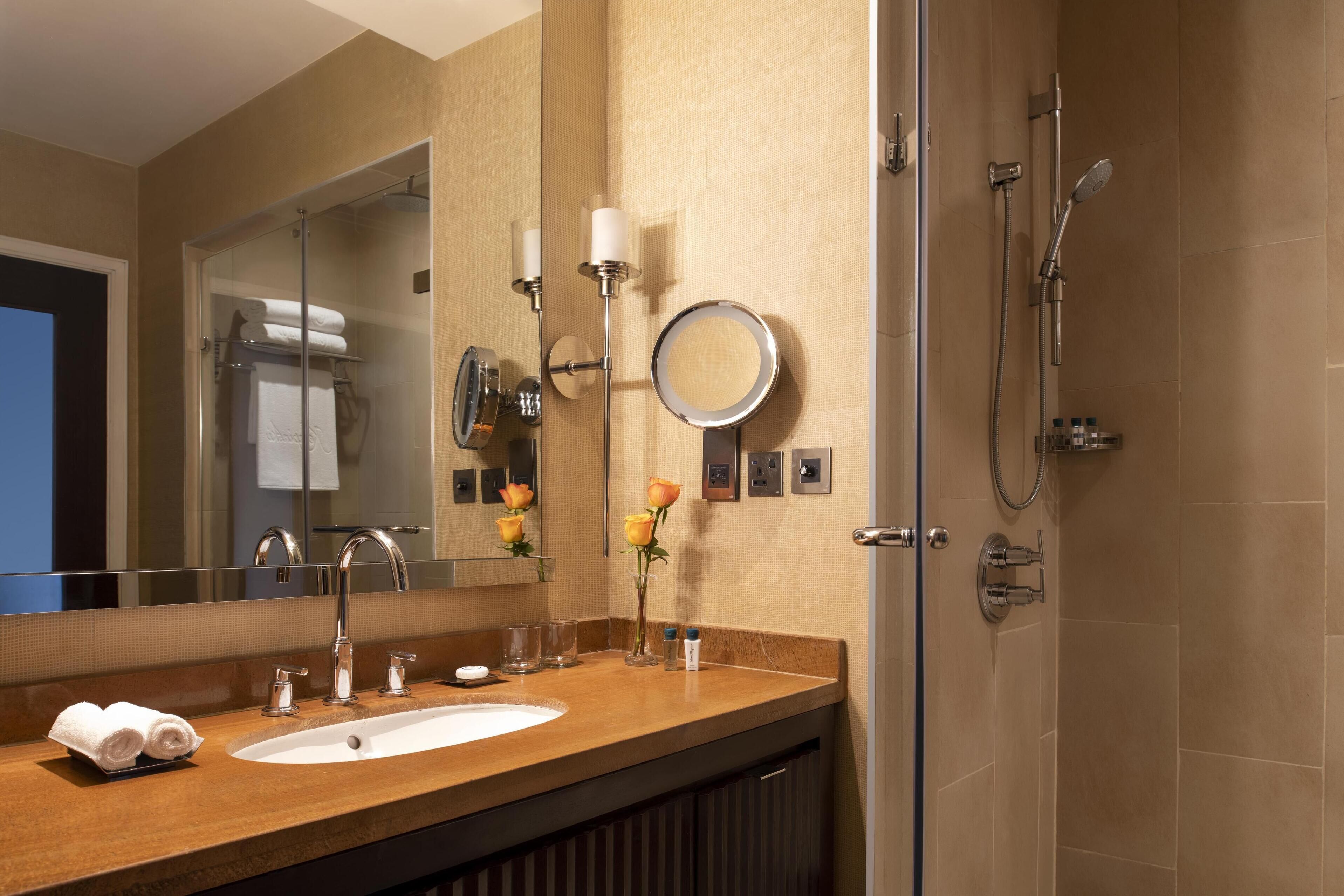 Une salle de bain équipée d’un lavabo, d’un miroir, d’un porte-serviettes et d’une douche.