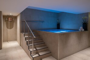 Une salle de bain moderne dotée d’un jacuzzi intégré, d’une douche à parois de verre et d’un design minimaliste.