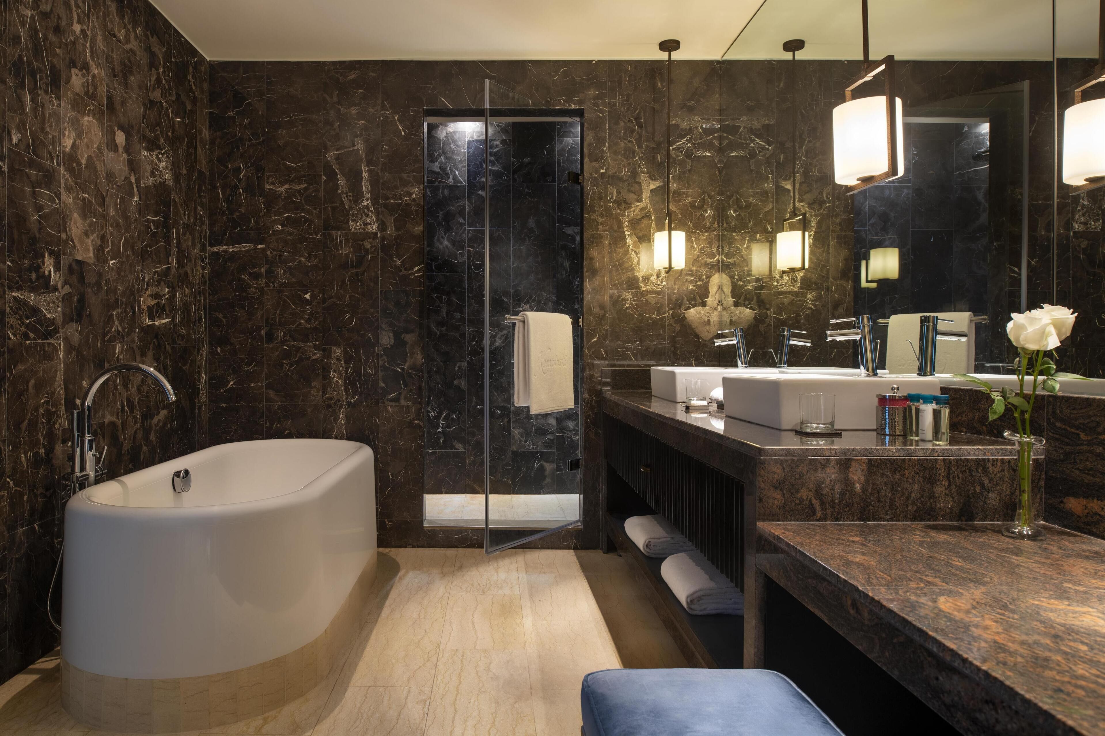 A modern bathroom with a large bathtub, a glass-enclosed shower, and a vanity with a mirror.