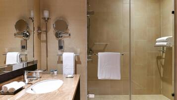 A modern bathroom with a large mirror, two round mirrors, a sink, and a glass-enclosed shower.