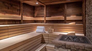 A wooden sauna with benches and a stone fireplace.