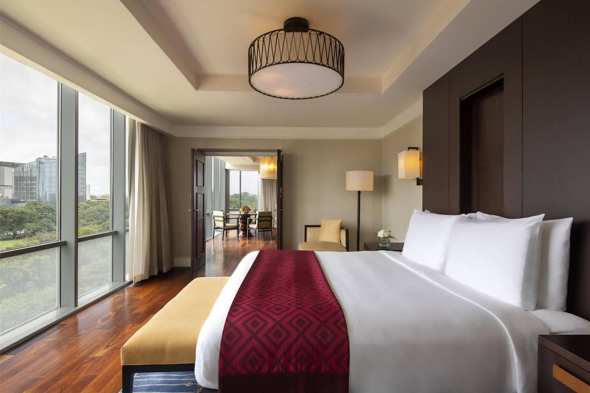 Ein Hotelzimmer mit einem großen Bett, Blick auf die Stadt und einem Balkon mit Tisch und Stühlen.