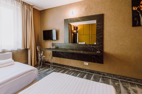 A hotel room with a bed, a desk with a mirror, a chair, and a television. - Ciao Hotel (Tirgu Mures)