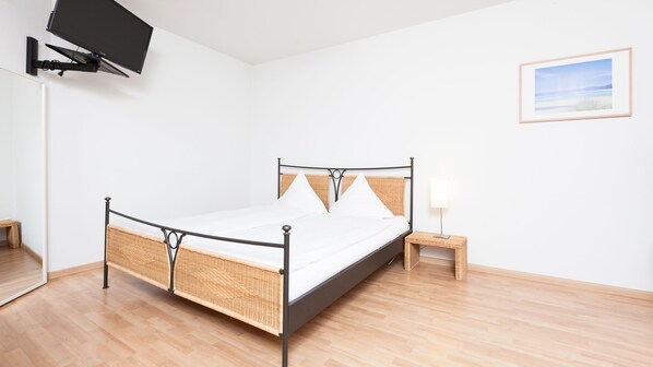 A modern bedroom with a bed, a small bedside table, a wall-mounted TV, and a framed picture on the wall. - Apartments Swiss Star Sihlfeld (Zürich)