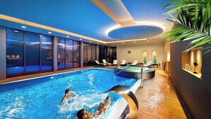 A swimming pool with a glass enclosure, lounge chairs, and a spa area. - Park Hotel (Dolny Kubin)