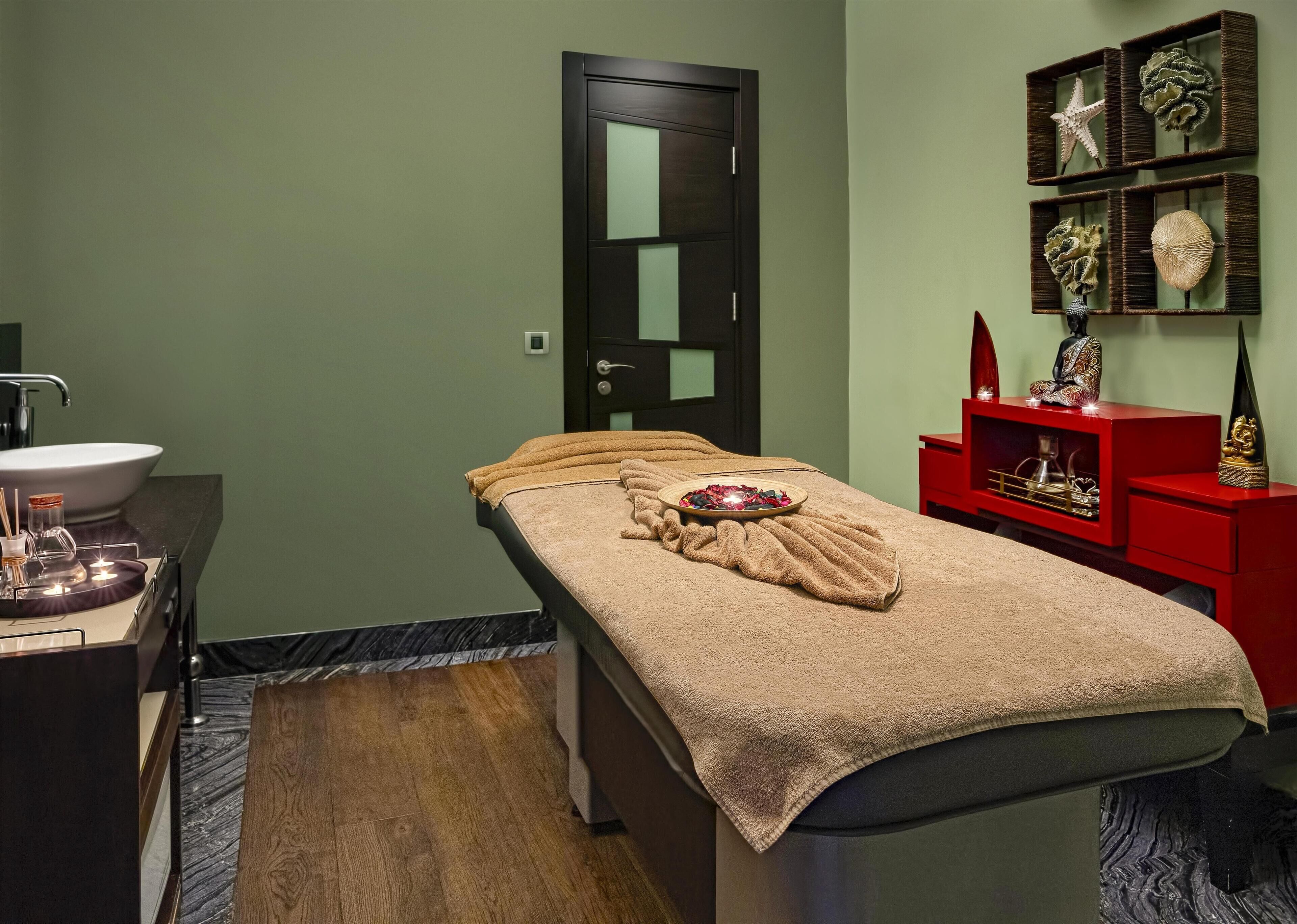 A room with a bed, a sink, and a red cabinet with decorative items.