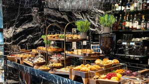 Un buffet proposant une variété de plats, notamment des pâtisseries et des fruits, présentés sur des présentoirs en bois et dans des vitrines en verre.