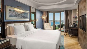Une chambre d’hôtel spacieuse, dotée d’un grand lit, d’un bureau et d’une chaise. La chambre offre une vue sur la ville grâce à de grandes fenêtres.
