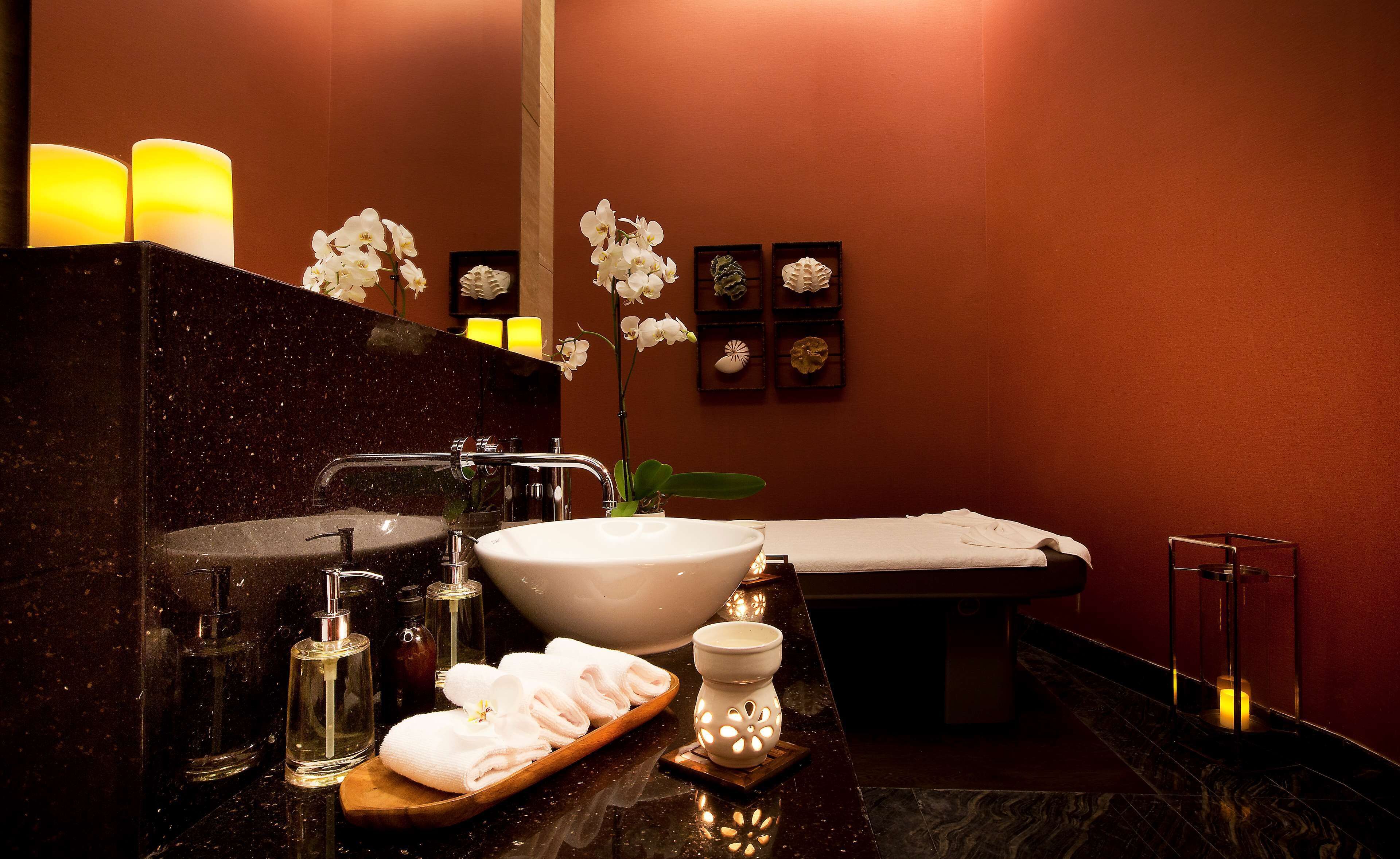 A bathroom with a large sink, a bathtub, and a mirror. There are candles, a bottle of hand soap, and a tray with towels.