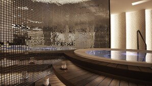 Un espace spa moderne doté d’un jacuzzi, d’un plancher en bois et d’une paroi en verre.