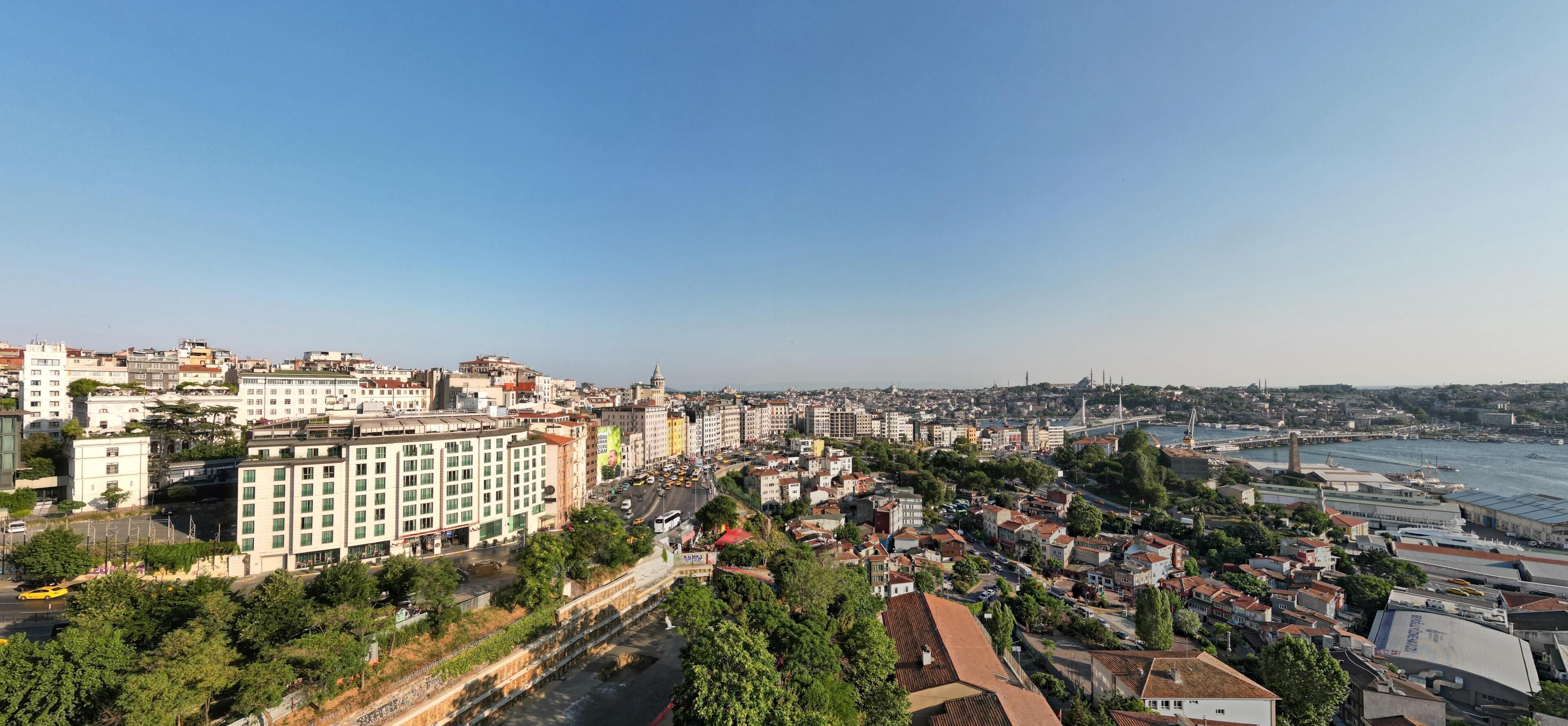 Un paisaje urbano costero con una mezcla de edificios residenciales y comerciales, un puente destacado y una vista despejada del mar.