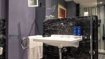 A modern bathroom with a marble sink, a glass shower enclosure, and a towel rack.