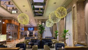 A modern hotel lobby with a central seating area, a staircase, and a restaurant in the background. - Sheraton Bursa Hotel (Bursa)