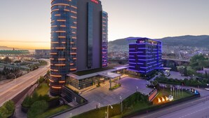 A Sheraton hotel with a modern design, featuring a curved facade and illuminated windows. - Sheraton Bursa Hotel (Bursa)