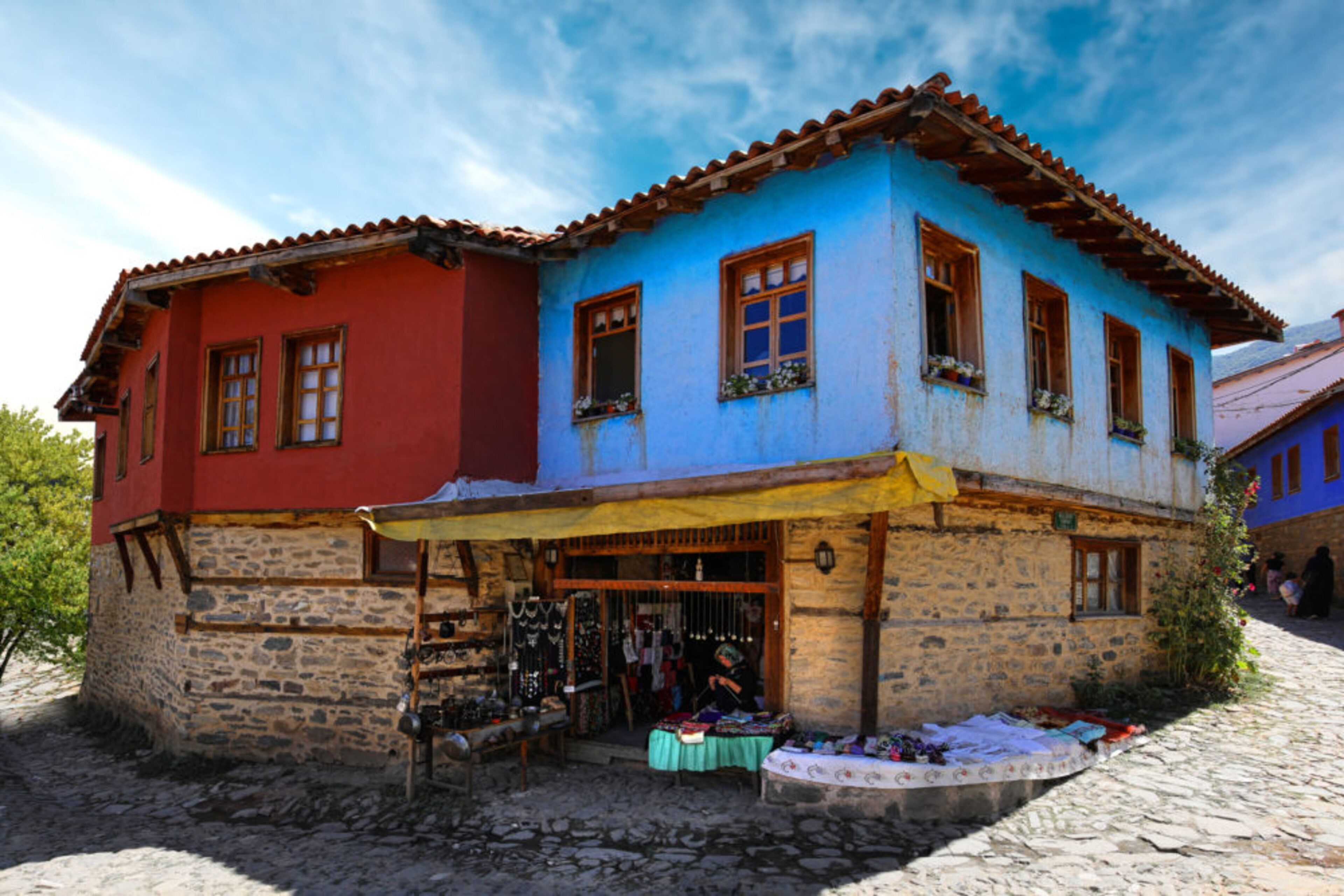 Un edificio de dos pisos con base de piedra y sección superior colorida, que cuenta con una tienda en la planta baja.