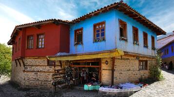 Un edificio de dos pisos con base de piedra y sección superior colorida, que cuenta con una tienda en la planta baja.