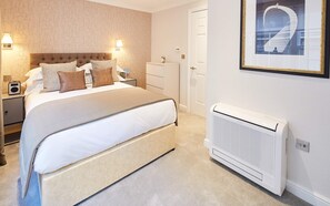 A neatly arranged bedroom with a bed, bedside tables, a radiator, and a framed picture on the wall. - Cheval Calico House (London)
