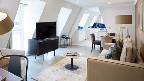 Una sala de estar moderna con un televisor de pantalla plana, un sofá, una mesa de centro y un comedor con sillas.