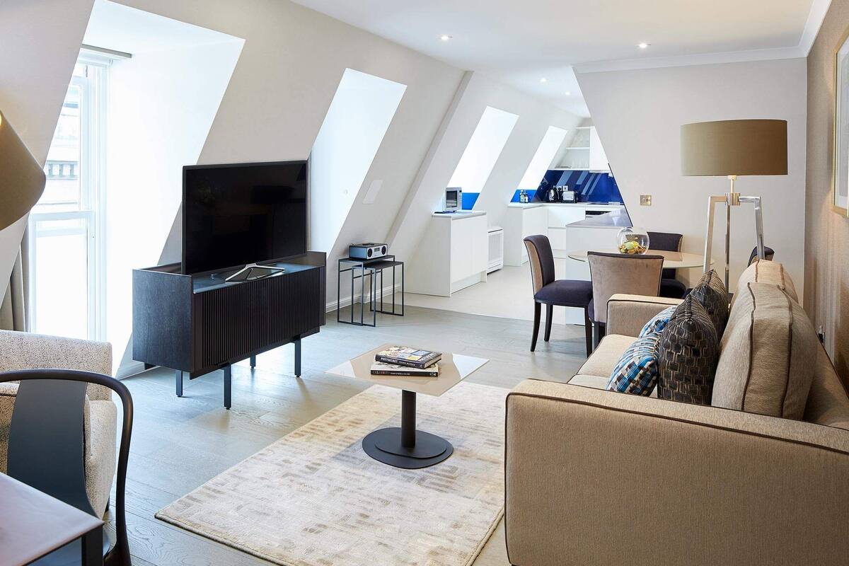Un salon moderne doté d’un téléviseur à écran plat, d’un canapé, d’une table basse et d’un coin repas avec des chaises.
