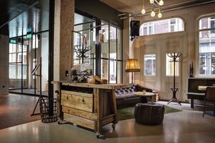 A cozy interior with a wooden bar, leather sofa, and large windows offering views of the street.