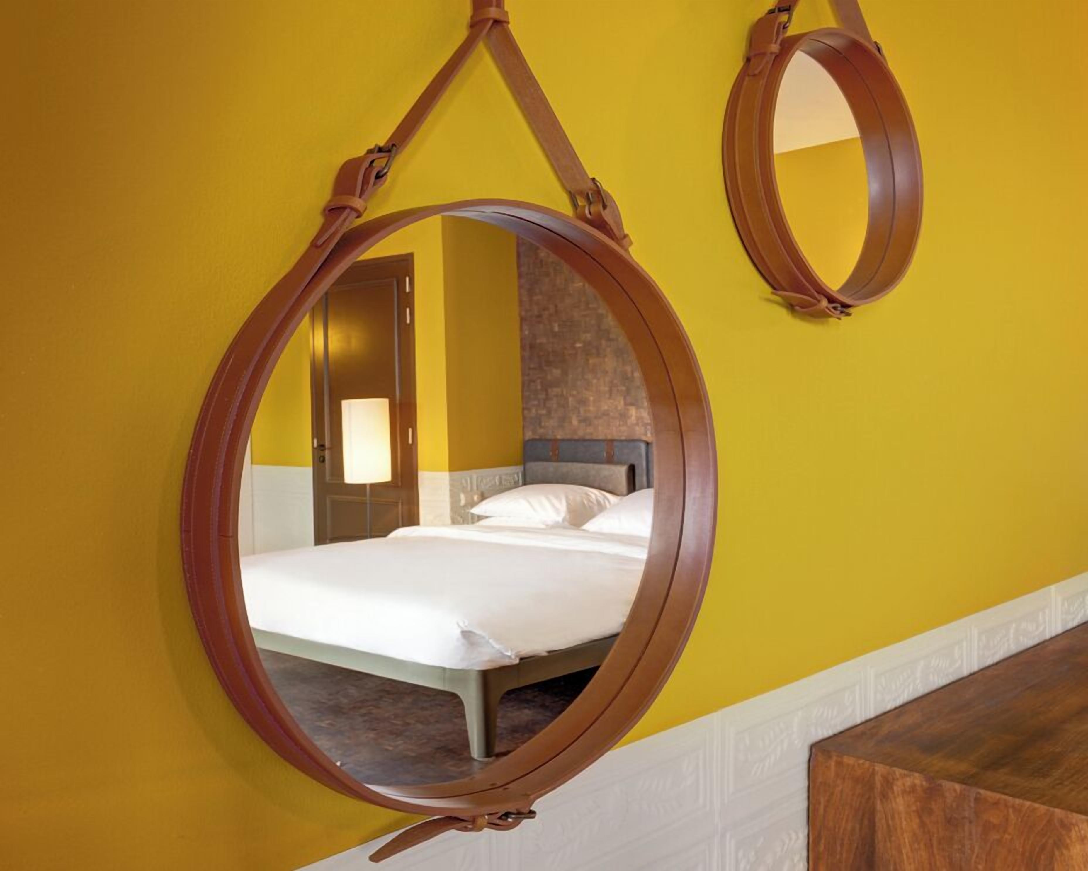 Una habitación con una cama, un espejo colgado y una puerta.