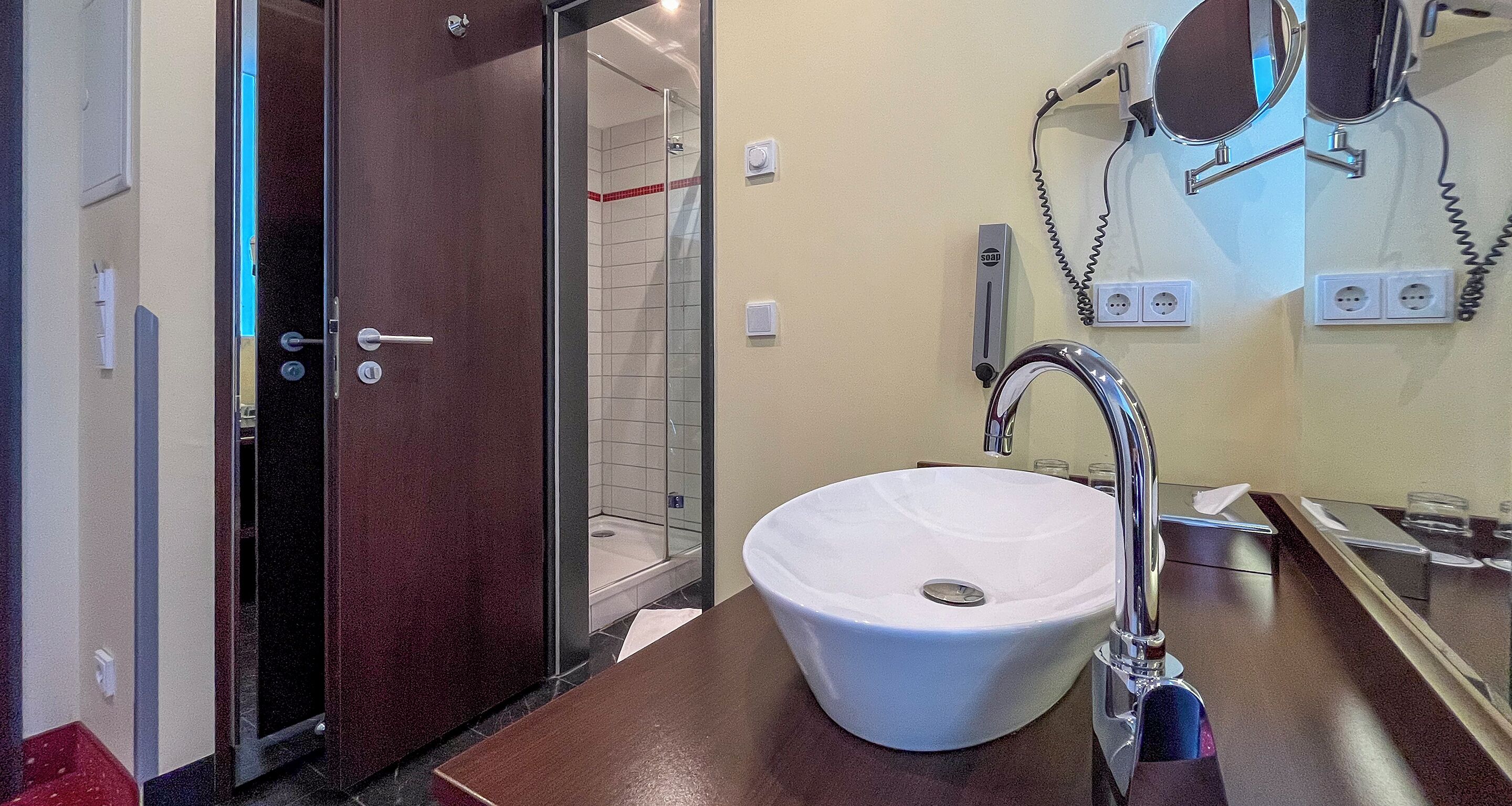 A bathroom with a white sink, a mirror, and a shower.