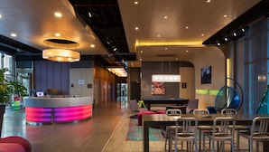 A modern lobby with a reception desk, seating area, and a large screen. - Aloft by Marriott Bursa Hotel (Bursa)