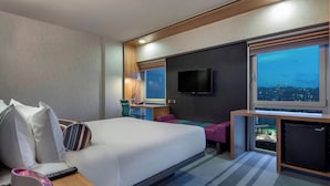 A hotel room with a bed, a desk, a TV, and a window with a city view. - Aloft by Marriott Bursa Hotel (Bursa)