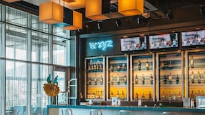 A bar area with a neon sign, multiple hanging lights, and a variety of seating options including bar stools and chairs. - Aloft by Marriott Bursa Hotel (Bursa)