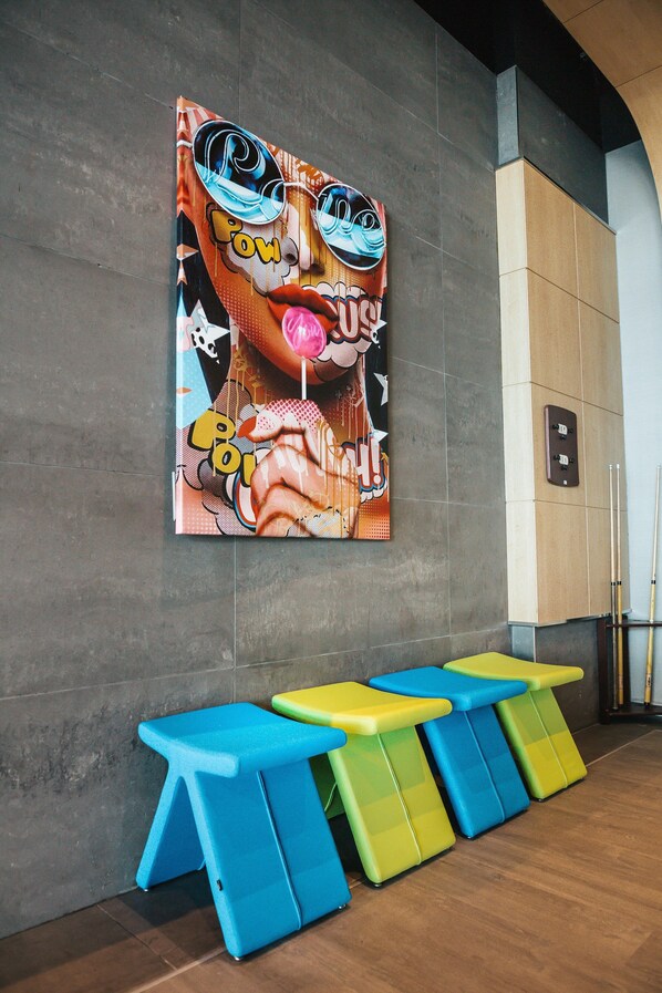 Una pared con una obra de arte colorida y una fila de taburetes de colores.