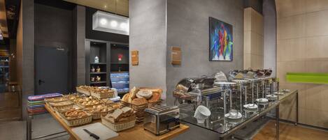A buffet setup with various food items and a painting on the wall.