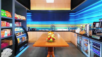 Una cocina moderna con una mesa de madera, vitrinas refrigeradas y estantes llenos de aperitivos.