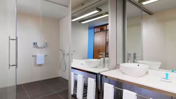 Un baño moderno con dos lavamanos, cabina de ducha de vidrio y un perchero para toallas.