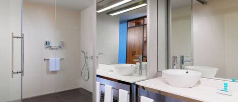 Un baño moderno con dos lavamanos, cabina de ducha de vidrio y un perchero para toallas.