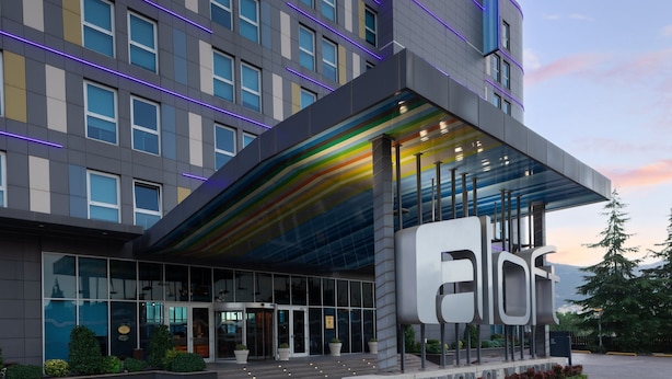 A modern building with a glass entrance and a large sign. - Aloft by Marriott Bursa Hotel (Bursa)