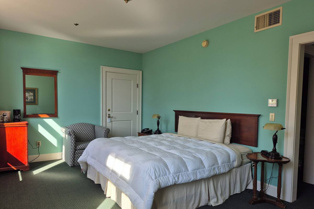Quarto com cama, cadeira, cômoda e abajur.