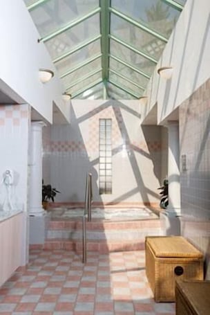 A modern interior with a checkered floor, a glass ceiling, and a staircase leading to a window.