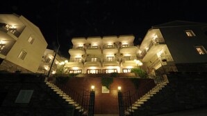 Een meerlaags hotel met een centrale binnenplaats, een trap die naar de ingang leidt, en een bordje waarop staat dat het een hotel is.
