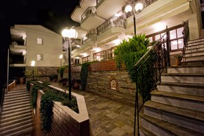 A hotel with multiple balconies, stone walls, and a well-lit entrance. - Lazaridis Luxury Apartments (Aristotelis)