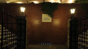 Een hotelentree met een bord waarop 'HOTEL LAZARIDIS' staat, een bakstenen muur en ijzeren hekken.