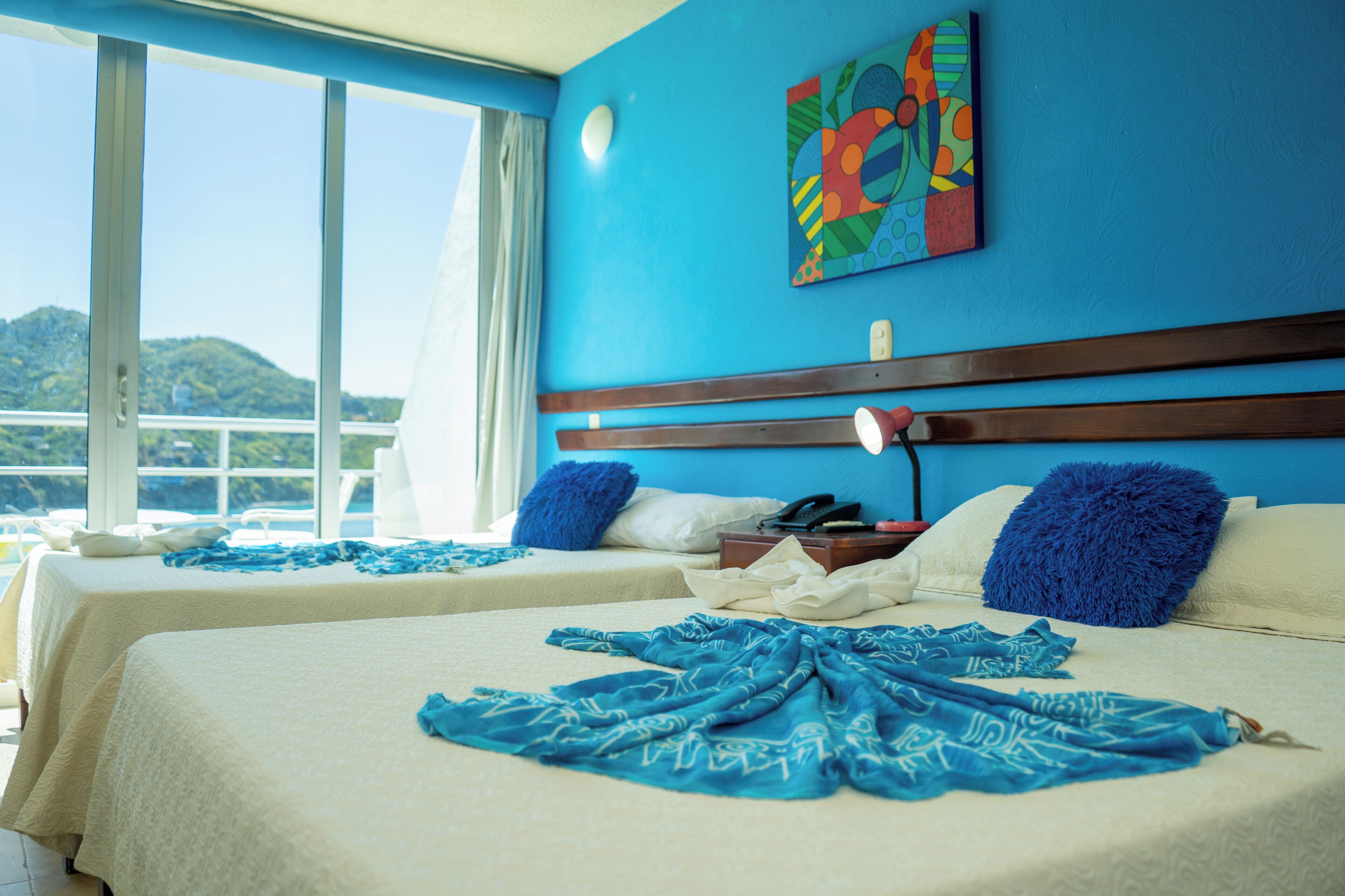 A hotel room with two beds, a large window, and a view of the mountains.