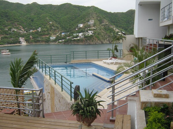 A swimming pool with a view of a hillside with houses. - Bahía Taganga Hotel (Santa Marta)