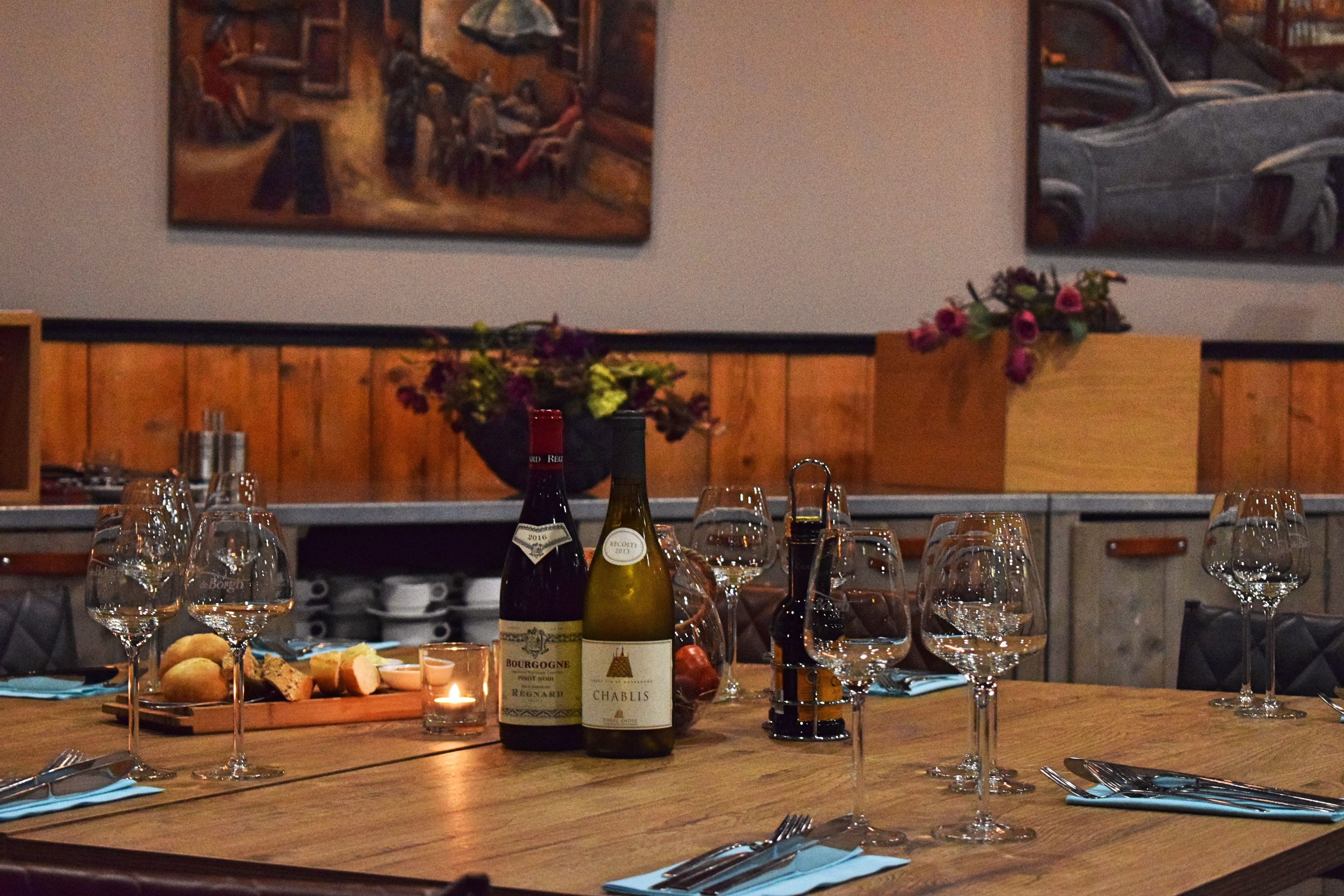 Ein mit Weingläsern, Flaschen und einer Kerze gedeckter Tisch im Restaurant.