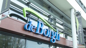 Exterior del hotel 'de Borge' con diseño moderno, gran cartel y fachada de vidrio.