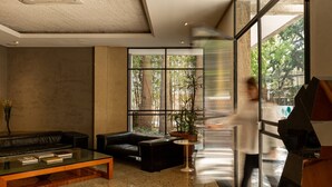 A modern lobby with a glass coffee table, leather sofas, and a large window offering a view of trees. - Alameda Apart Hotel (São Paulo)