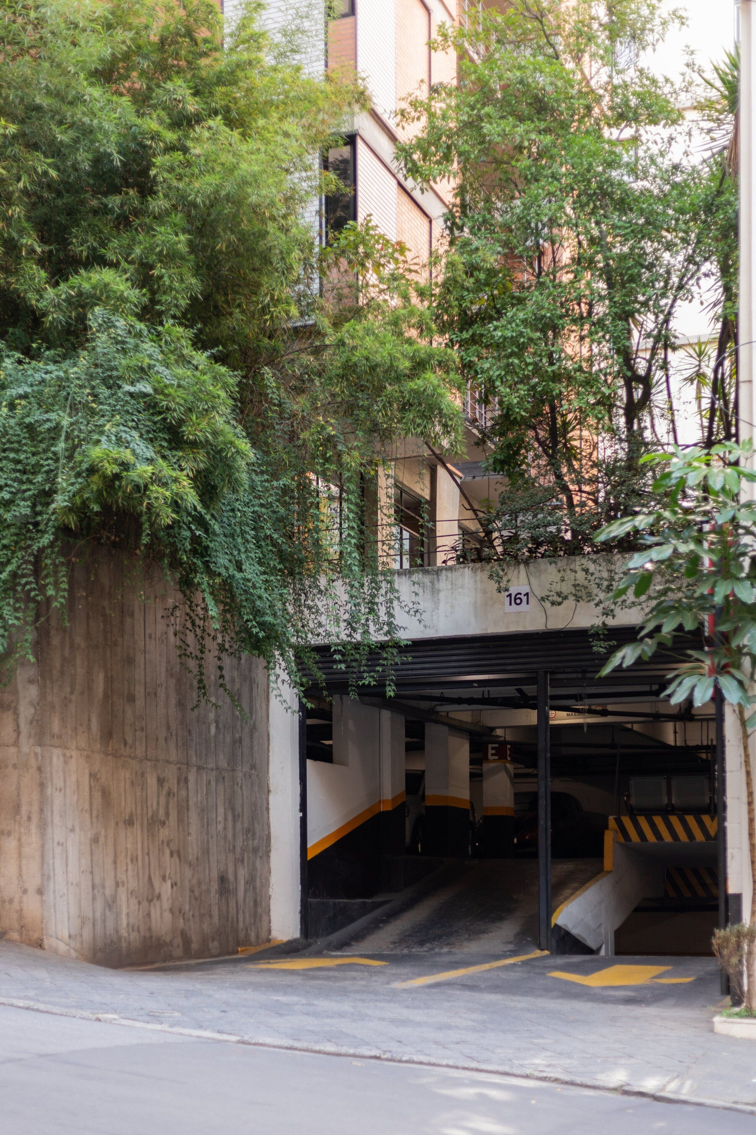 A multi-level parking garage with a concrete wall and a staircase leading to the upper levels.