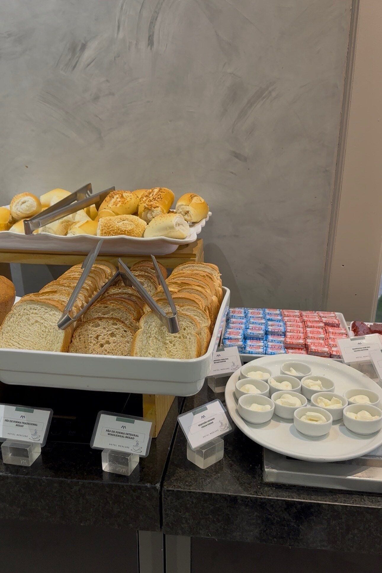 Un bufé con panes, pasteles y salsas diversas.