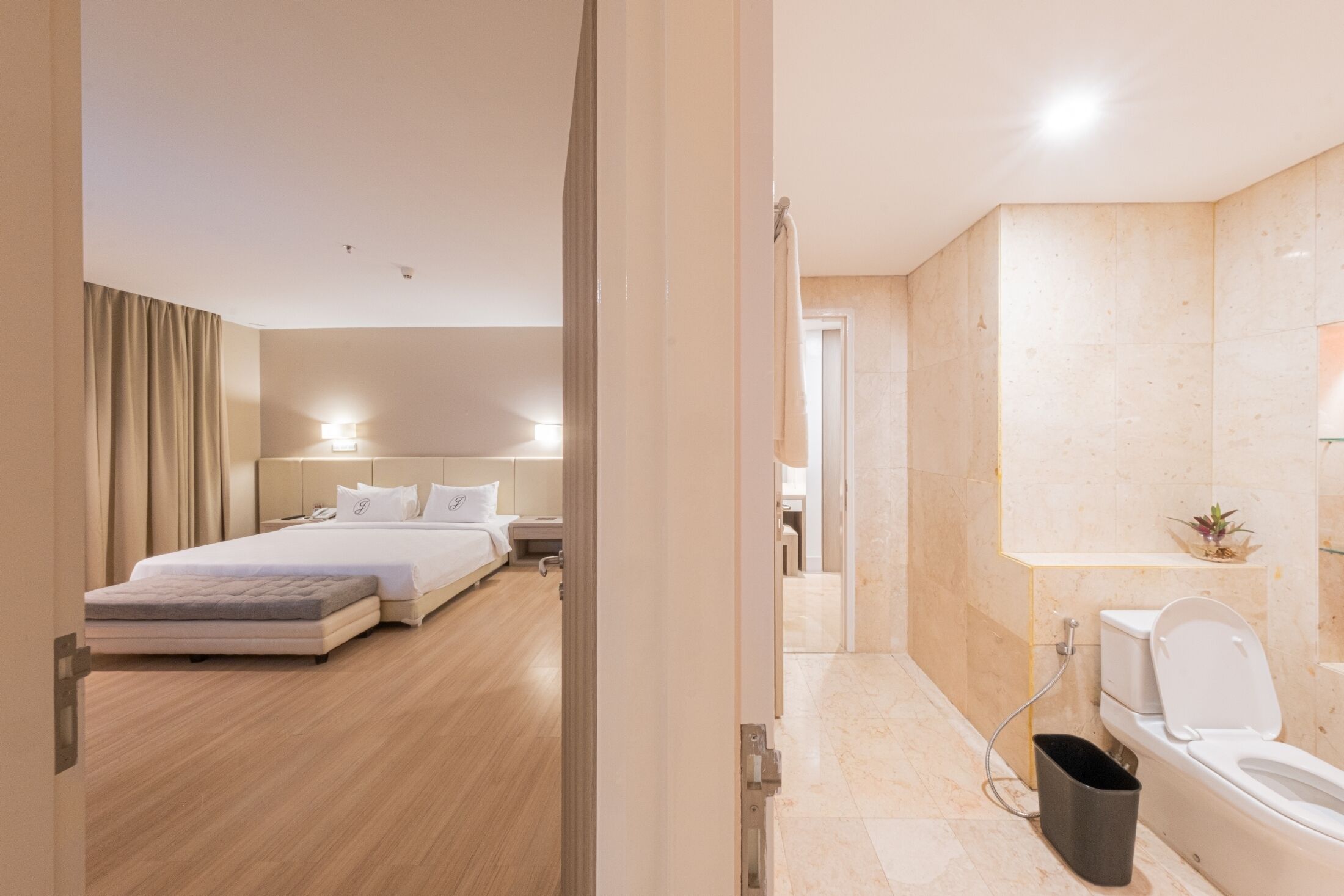 Een moderne hotelkamer met een bed, nachtkastje en een badkamer met toilet en wastafel.