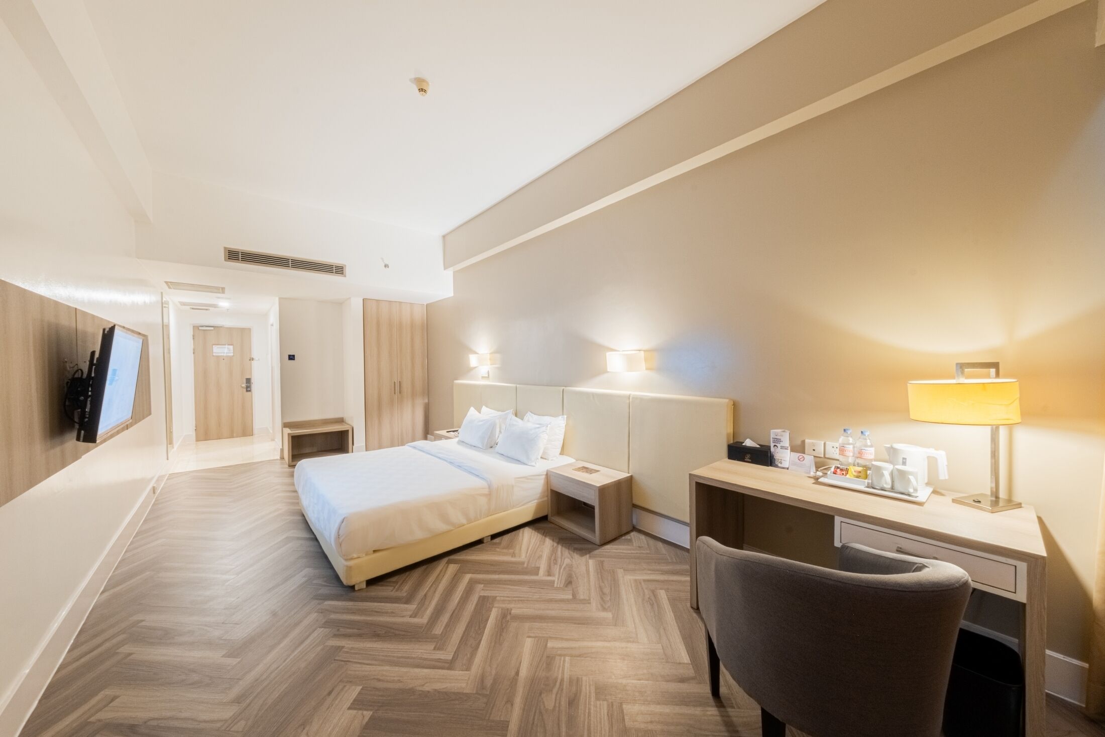 Habitación de hotel con cama, escritorio, silla y lámparas de noche.