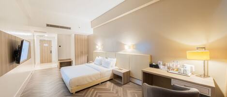 Habitación de hotel con cama, escritorio, silla y lámparas de noche.